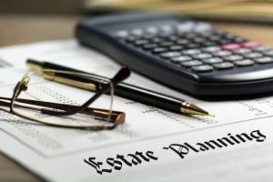 calculator, pen and glasses sitting on top of an estate planning document
