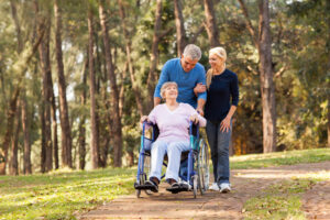caring couple taking their disable senior mother for a walk at the park